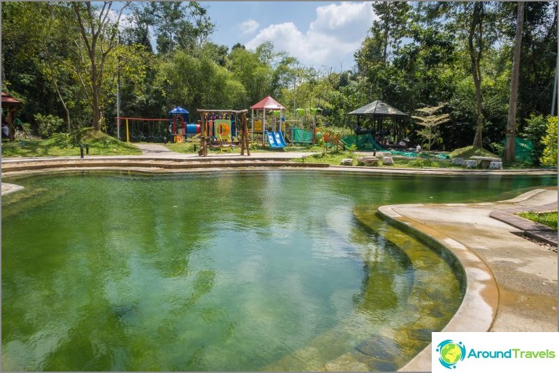 Detrás de la piscina se puede ver el parque infantil.