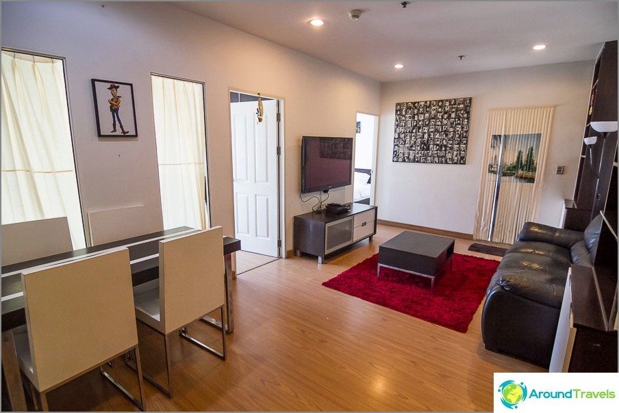 Living room with large TV, sofa and dining table