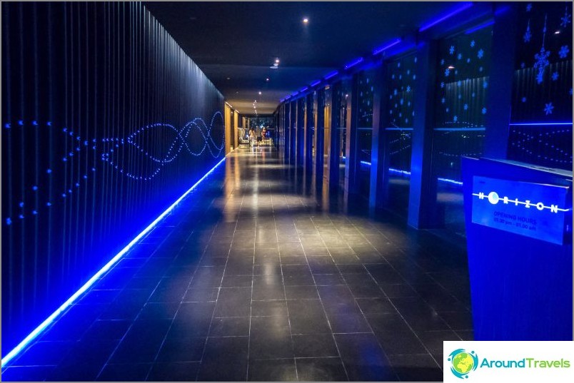 A dark, illuminated corridor leads to the restaurant