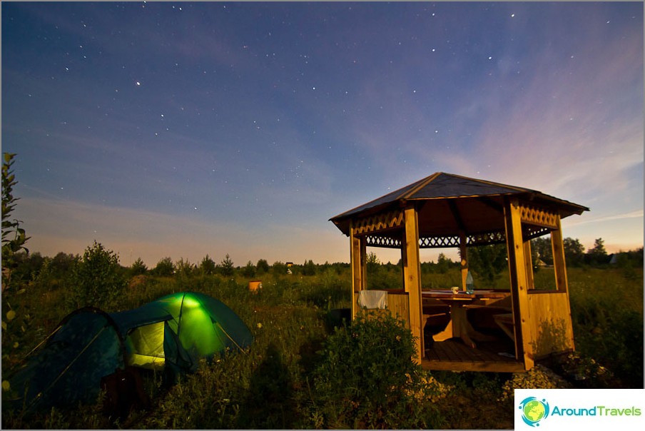 Het tuinhuisje wordt verlicht door de maan, de tent zit in een zaklamp