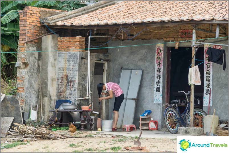 A girl washes her hair in a bucket on the porch of her house